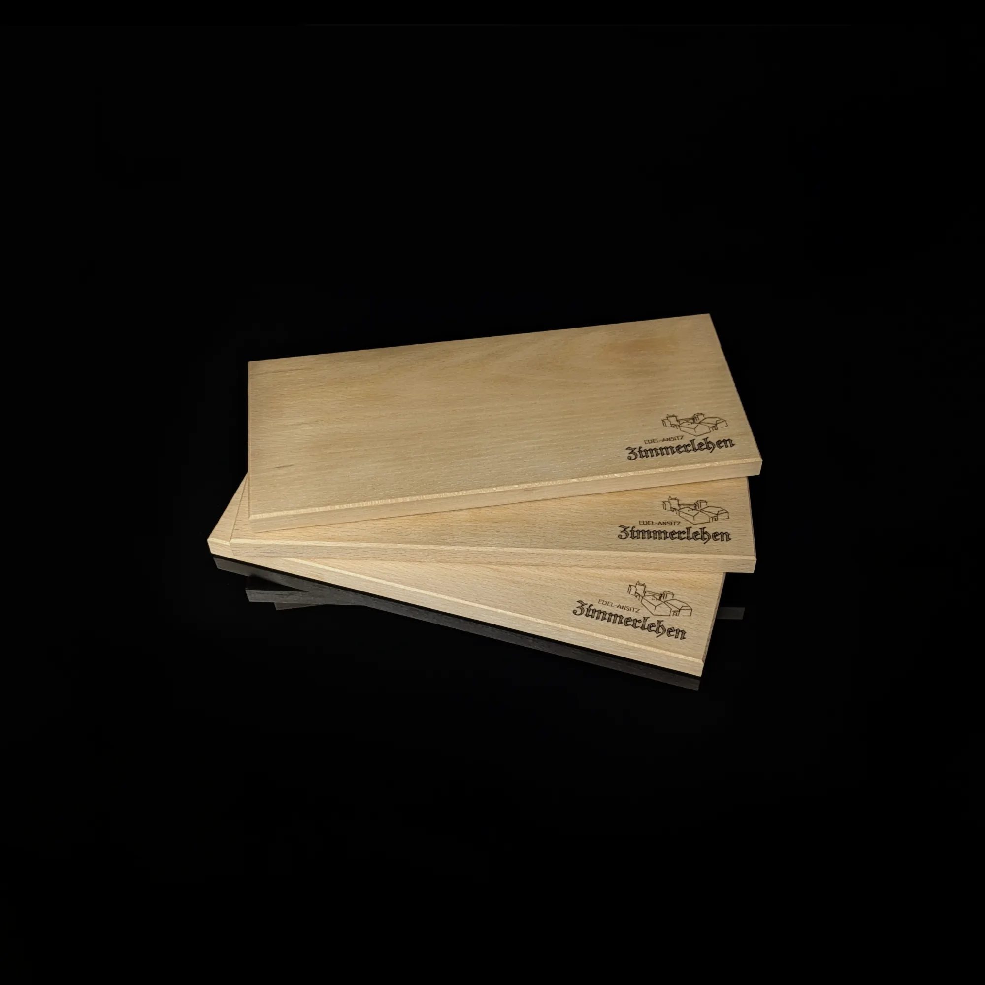 Three wooden boards, each with a laser-engraved logo on a black background. Click on the picture to go to the subpage 'Engravings'.